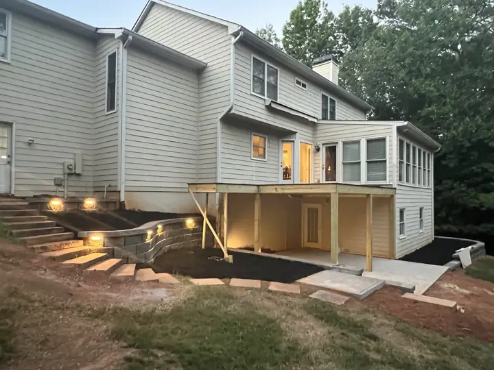 Finished backyard by Oscar Cruz Construction: new deck with lit steps, block retaining wall and concrete patio